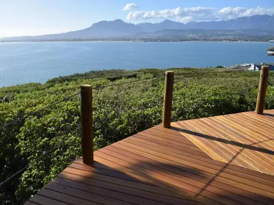 a wooden deck with a view of the water at Artists Cottages Gordon's Bay in Cape Town