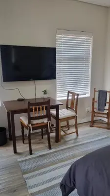 a living room with a table and chairs and a tv at Lorenza's Place in Stellenbosch