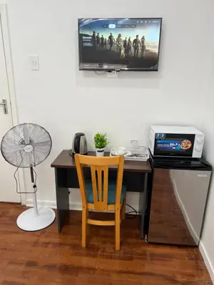a desk with a laptop and a television on a wall at Botha Villa Lodge Goodwood in Cape Town
