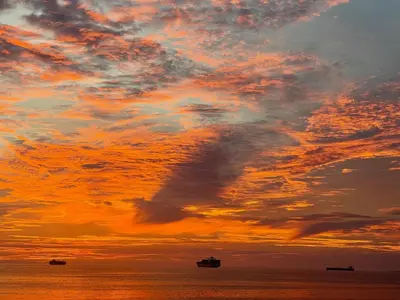 a sunset with two boats in the ocean at Blouberg Sea View in Bloubergstrand