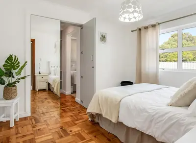 a white bedroom with a bed and a mirror at Kiefern Haus Main House in Cape Town