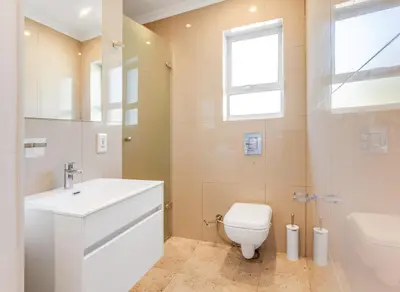 a bathroom with a toilet and a sink and a window at Kiefern Haus Main House in Cape Town