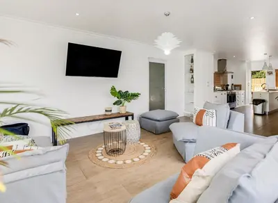 a living room with couches and a tv on the wall at Kiefern Haus Main House in Cape Town