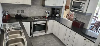 a small kitchen with a stove and a microwave at Picollo Bocca Villa Kleinmond in Kleinmond