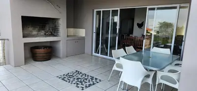 a dining room with a glass table and white chairs at Picollo Bocca Villa Kleinmond in Kleinmond
