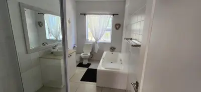 a white bathroom with a toilet and a sink at Picollo Bocca Villa Kleinmond in Kleinmond