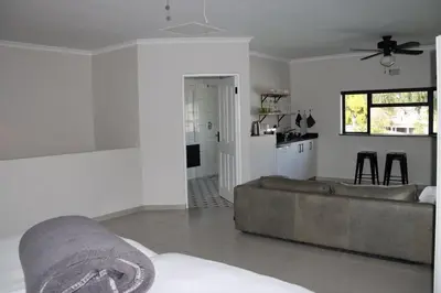 a living room with a couch and a kitchen at Villa Des Roses in Paarl