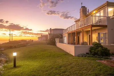 a house with a light pole in the grass at House 12 Beach Club in Hermanus