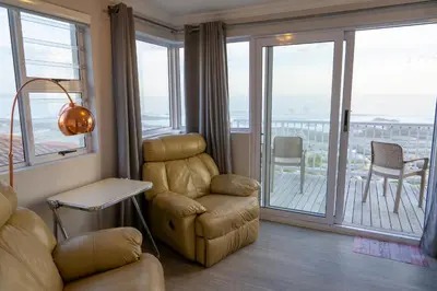 a living room with a couch and a chair and a balcony at House 12 Beach Club in Hermanus