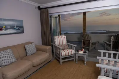 a living room with a couch and chairs and a balcony at House 12 Beach Club in Hermanus
