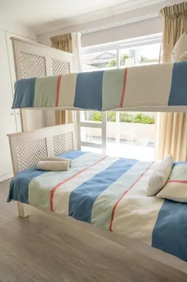 a bedroom with two bunk beds and a window at House 12 Beach Club in Hermanus