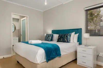a bedroom with a large bed with a blue headboard at Mayfair Apartments in Cape Town