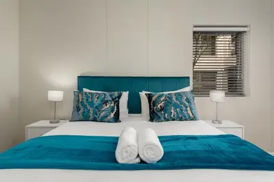 a bedroom with a blue bed with two white towels at Mayfair Apartments in Cape Town