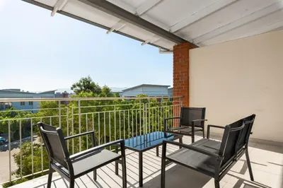 three chairs and a table on a balcony at Mayfair Apartments in Cape Town