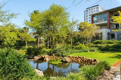 a garden with a pond in front of a building at Mayfair Apartments in Cape Town