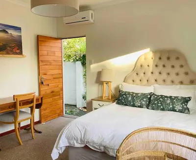 a bedroom with a large bed with a desk and a window at Garden studio close to Wine Farms in Somerset West