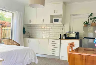a kitchen with white cabinets and a bed and a microwave at Garden studio close to Wine Farms in Somerset West