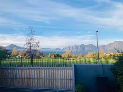 a fence with a view of a lake and mountains at Garden studio close to Wine Farms in Somerset West