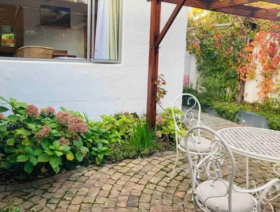 a patio with a table and chairs and flowers at Garden studio close to Wine Farms in Somerset West