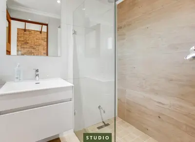 a white bathroom with a sink and a shower at Kiefern Haus Studio Apartment in Cape Town