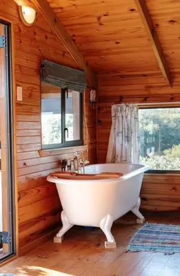 a white bath tub in a wooden room with a window at Flock-Inn in Fisherhaven