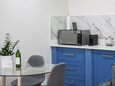 a kitchen with a table with a microwave and chairs at La Dolce Vita Gordon’s Bay in Gordonʼs Bay