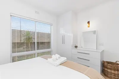 a white bedroom with a bed and a window at Leisure Bay 117 in Cape Town