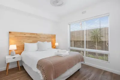 a white bedroom with a bed and a window at Leisure Bay 117 in Cape Town
