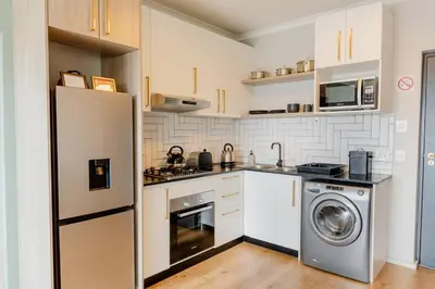 a kitchen with a refrigerator and a washing machine at Sunny Beach Apartment with Sea & Mountain Views in Cape Town