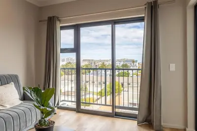 a living room with a couch and a large window at Sunny Beach Apartment with Sea & Mountain Views in Cape Town
