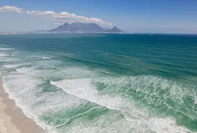 an aerial view of a beach with a mountain in the background at Sunny Beach Apartment with Sea & Mountain Views in Cape Town