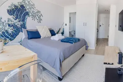 a bedroom with a large bed with blue pillows at Beach & Sea View Facing Apartment Japanese Styled in Cape Town