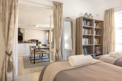 a bedroom with two beds and a table and a kitchen at Inn 201 in Hermanus
