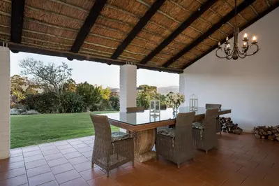 an outdoor dining room with a wooden table and chairs at La Felicita Boutique Self Catering Villas in Somerset West