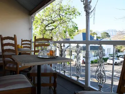 a table and chairs on a balcony with a view of a street at Petites Bulles Lodge in Stellenbosch