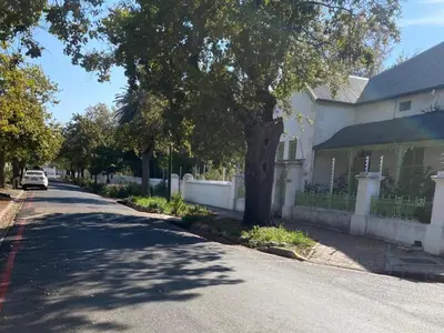 a street in front of a white house with a tree at Petites Bulles Lodge in Stellenbosch