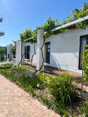 a white house with a brick driveway at Chasselas Self Catering in Cape Town