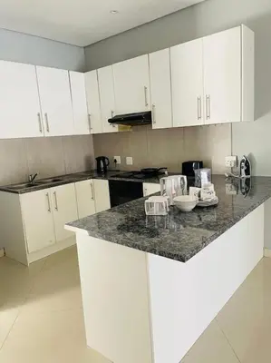 a kitchen with white cabinets and a granite counter top at Rachel`s Guest House - Cape Town in Cape Town