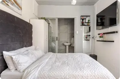 a bedroom with a white bed and a bathroom at A Room with private Entrance in Cape Town