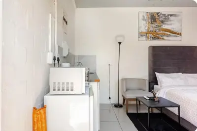 a small bedroom with a bed and a microwave on a refrigerator at A Room with private Entrance in Cape Town