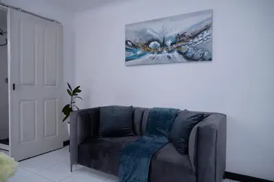 a couch in a living room with a painting on the wall at Blomtuin Sleep and go room in Cape Town