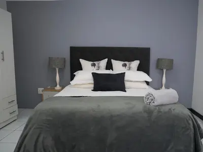 a bedroom with a large bed with black and white pillows at Blomtuin Sleep and go room in Cape Town