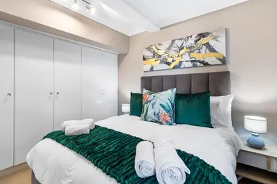 a bedroom with a large bed with green accents at 9 On The Waves in Cape Town