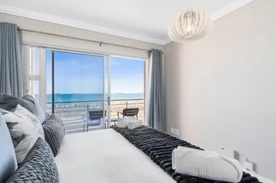 a bedroom with a large window with a view of the ocean at 9 On The Waves in Cape Town