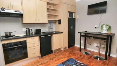 a kitchen with wooden cabinets and a black refrigerator at Royal Beauty in Paarl