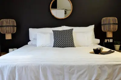 a bedroom with a white bed with a mirror on the wall at Olive Grove on Provident in Cape Town