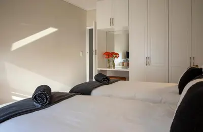 two beds in a room with white cabinets at Twin Gables, centrally located 2 bedroom apartment in Hermanus