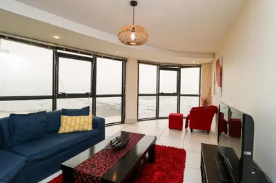 a living room with a blue couch and red chairs at Ocean View 304 Luxury Self Catering Apartment Strand Western Cape South Africa in Cape Town
