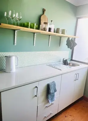 a kitchen with white cabinets and a sink at Rondebosch Cottage in Cape Town