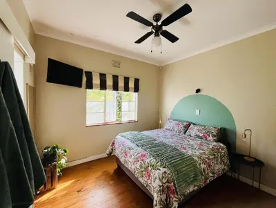 a bedroom with a bed and a ceiling fan at Rondebosch Cottage in Cape Town